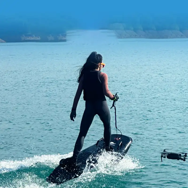 Woman riding motorized surfboard on water