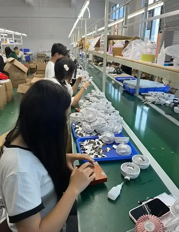 Workers assembling portable fans on a production line in Guangdong — labor cost is typically 15-25% of a factory's unit price