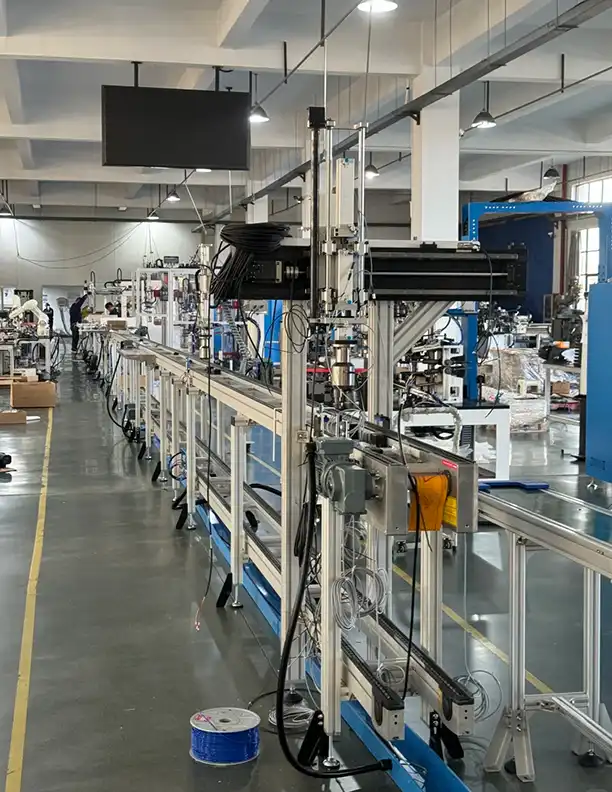 Automated assembly line with robotic arms — at sufficient volume, per-unit labor cost drops dramatically through automation